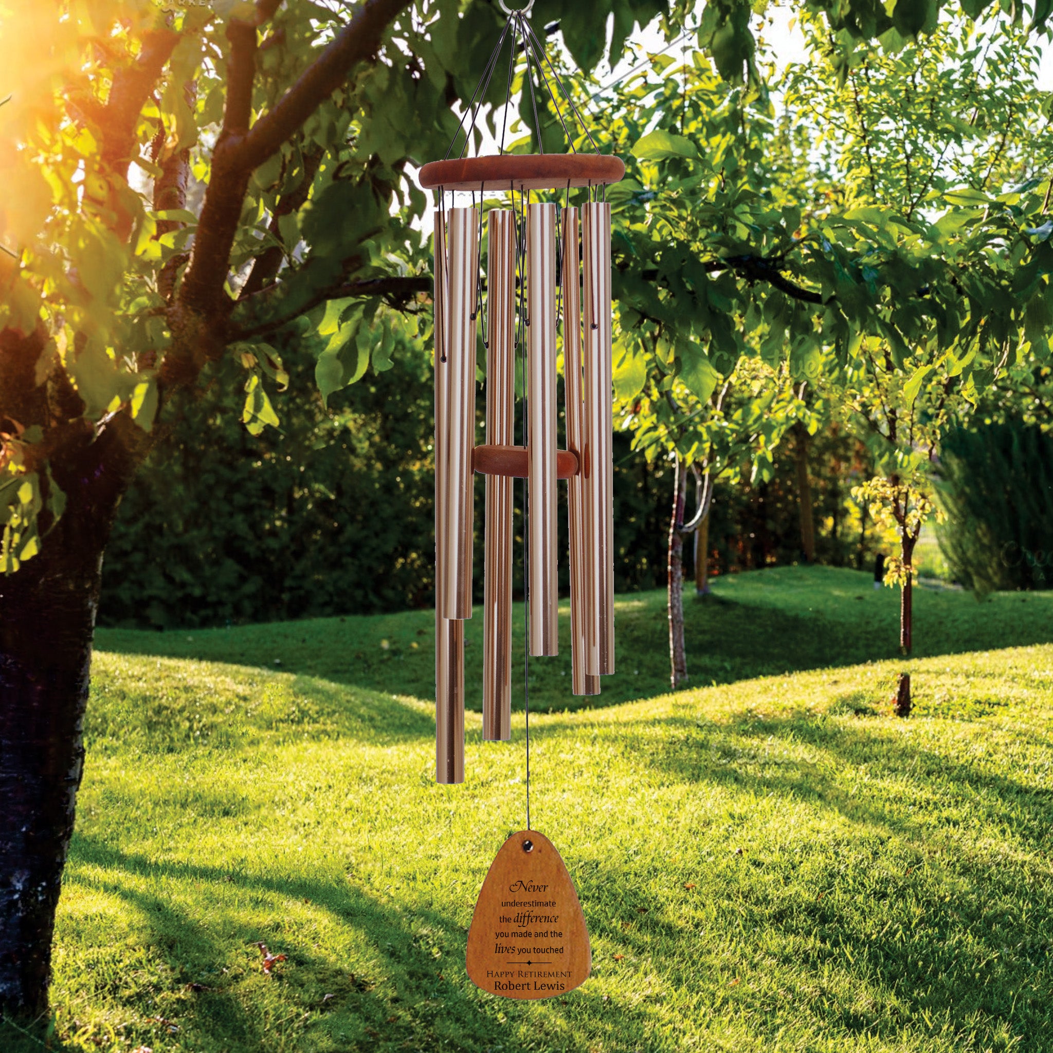 Wood Wind chime with bronze tubes hanging from a tree in a garden